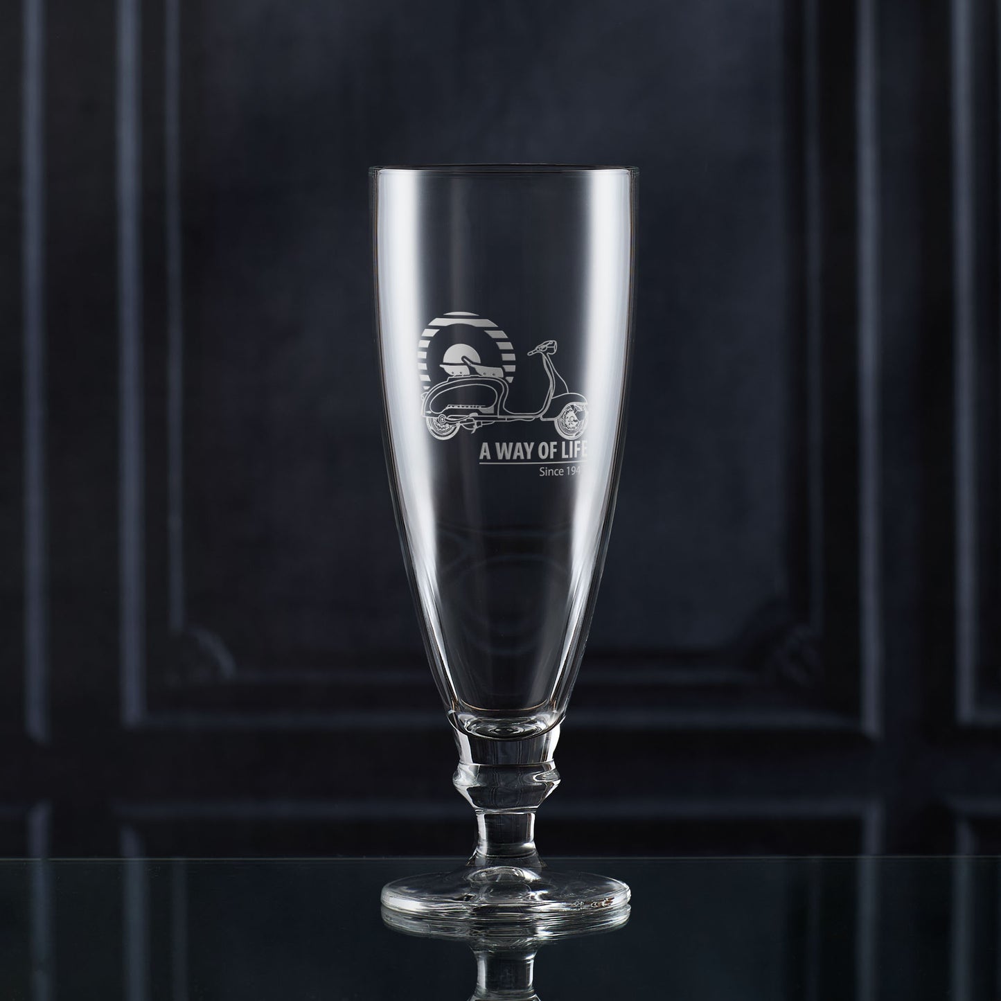 Stemmed glass with engraved scooter design and text on a dark background