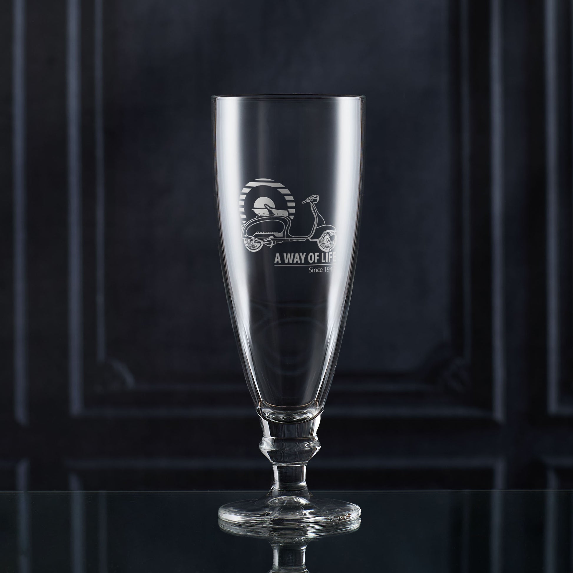 Stemmed glass with engraved scooter design and text on a dark background