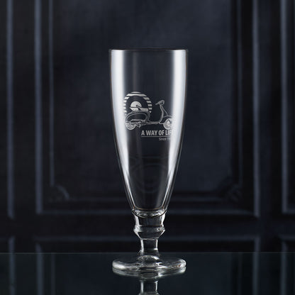 Stemmed glass with engraved scooter design and text on a dark background
