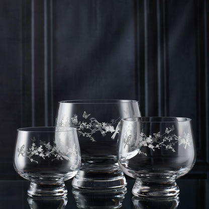 Three glass tulip bowls with floral engraving on a dark background