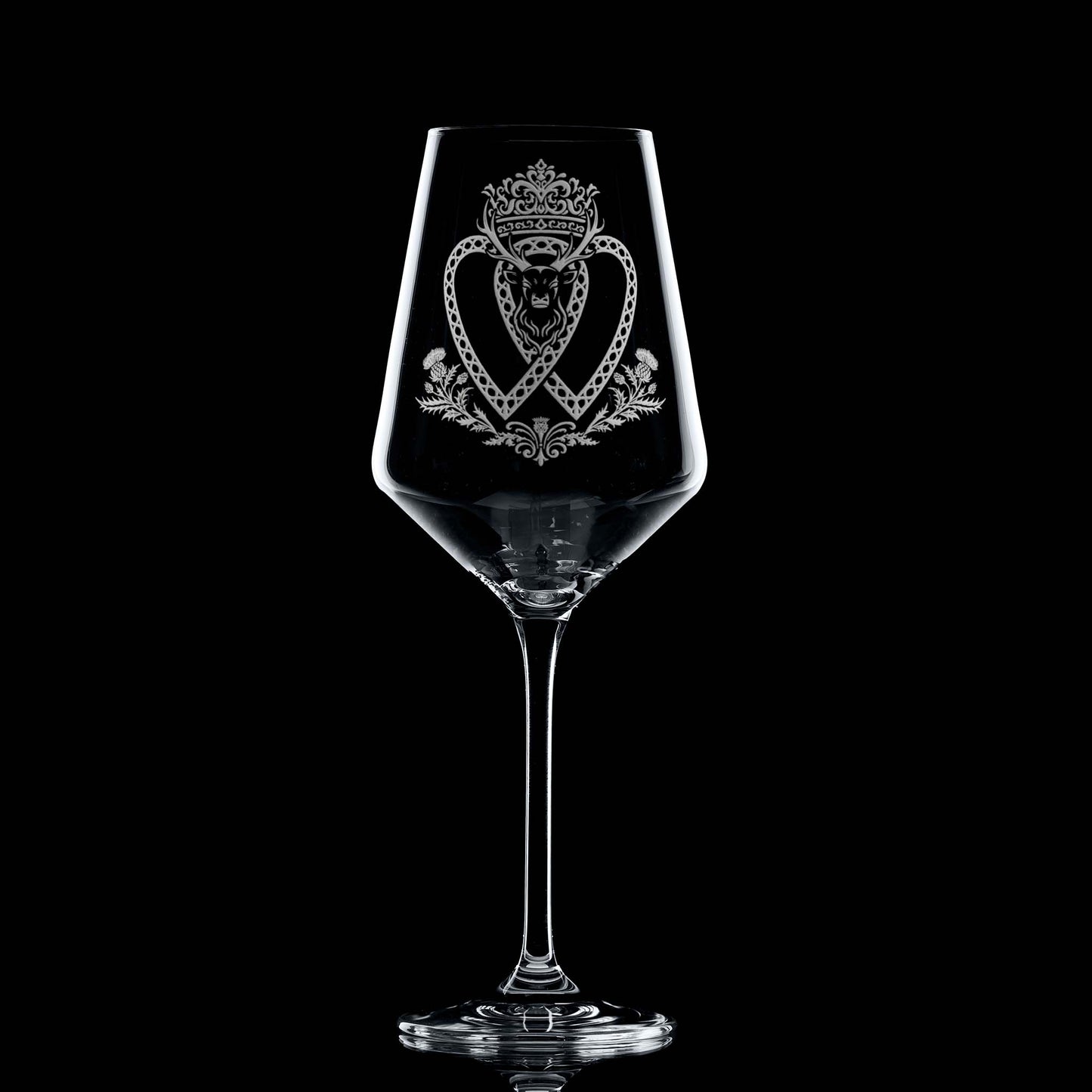 Atelier Edition wine glass engraved with a crowned Luckenbooth, thistles, and stag motif, shown on black background to highlight engraving detail