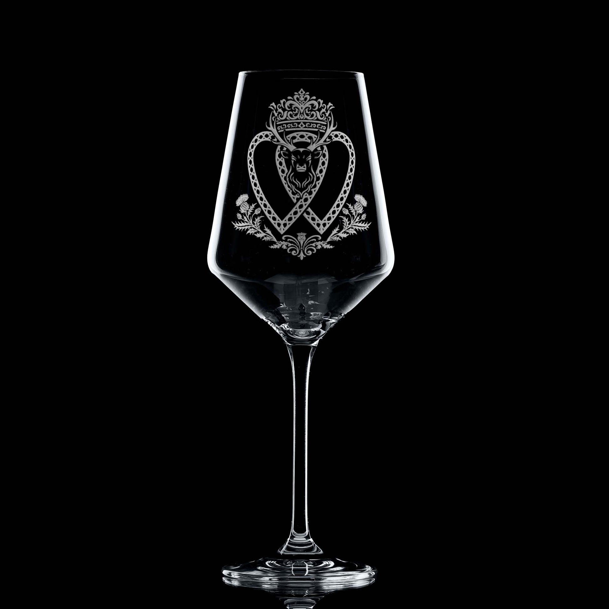 Atelier Edition wine glass engraved with a crowned Luckenbooth, thistles, and stag motif, shown on black background to highlight engraving detail