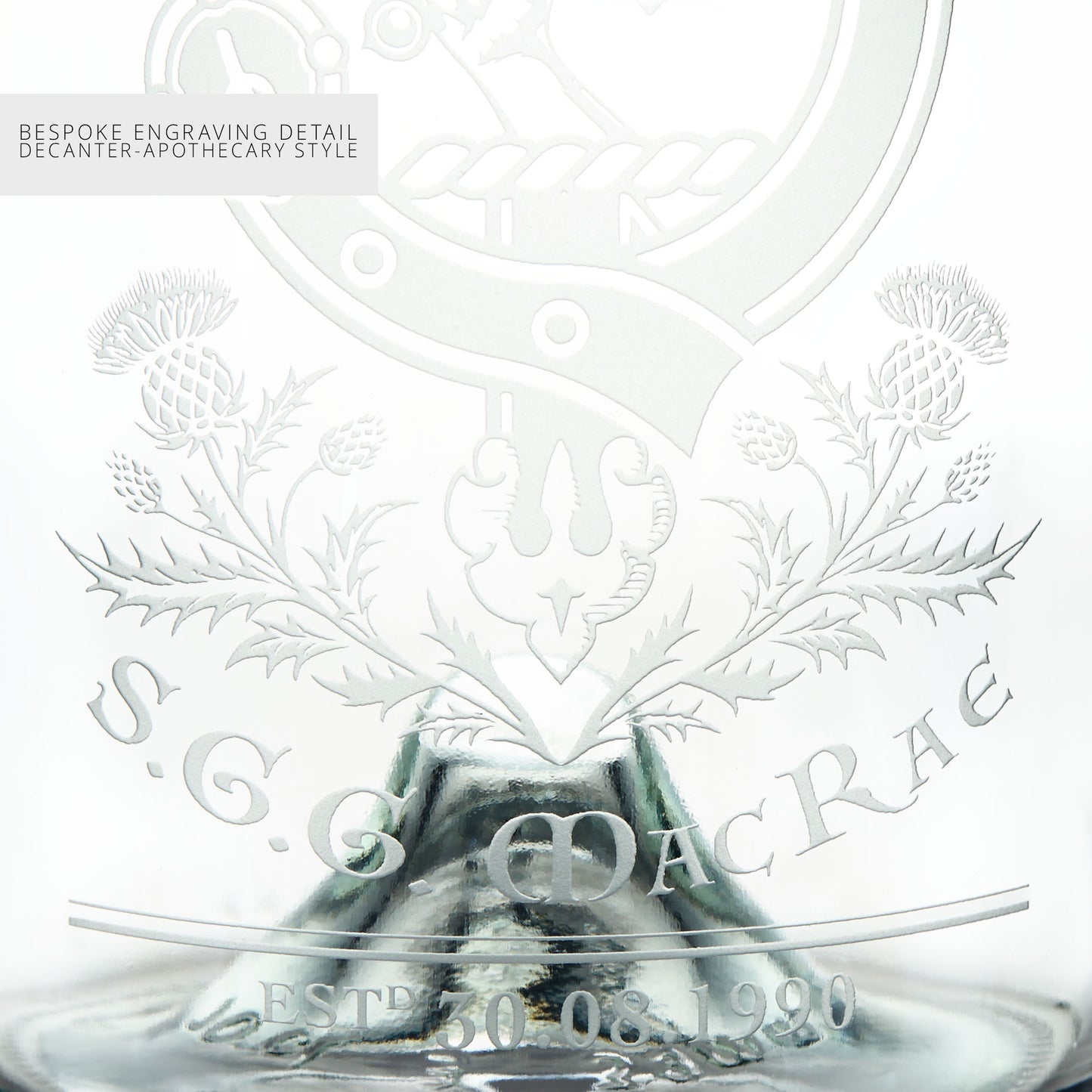 Close-up detail of a glass decanter with intricate engravings and personalised text on a white background