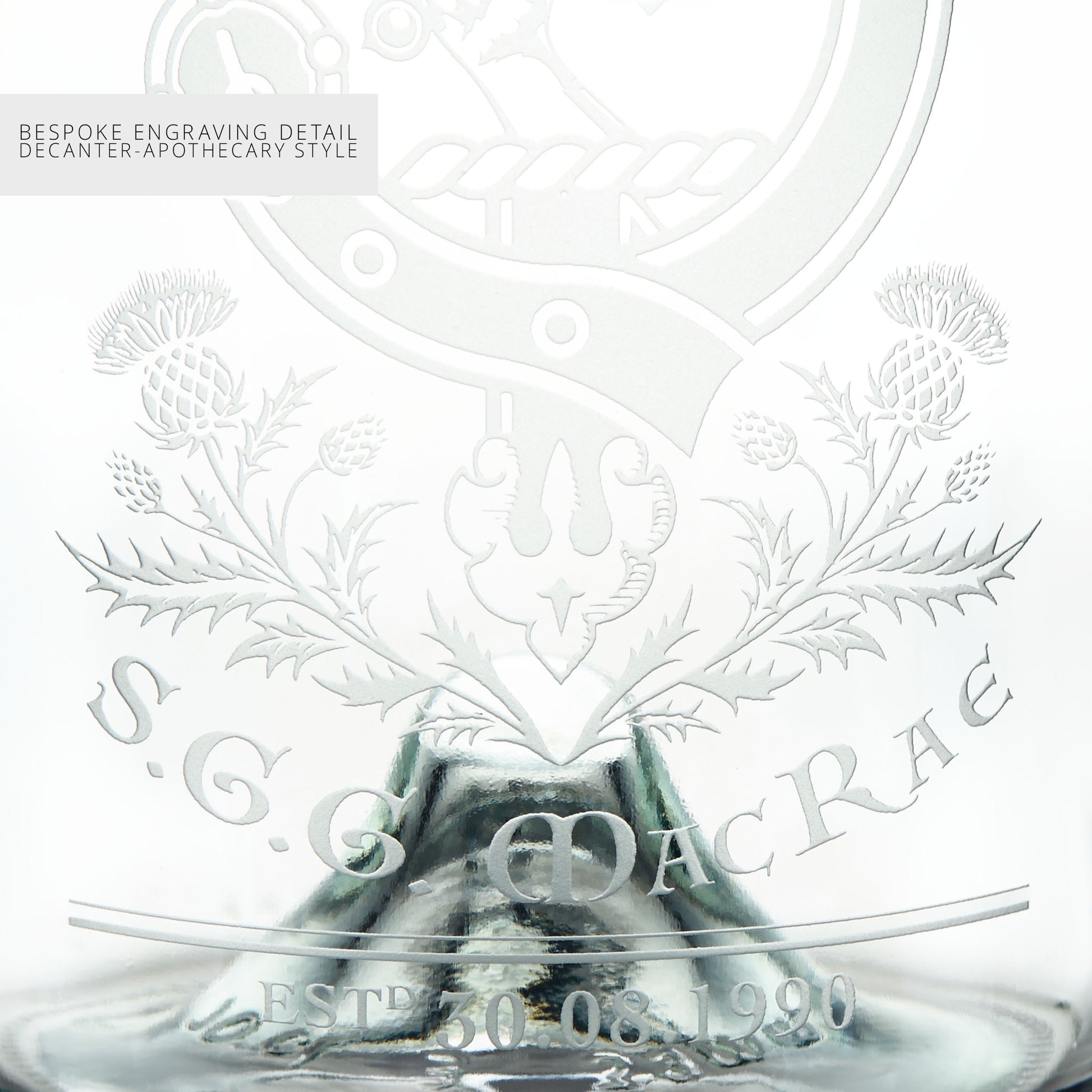 Close-up detail of a glass decanter with intricate engravings and personalised text on a white background