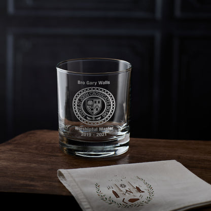 Freemasonss whisky glass engraved with personalised masonic lodge crest and text. On wooden surface with a dark background