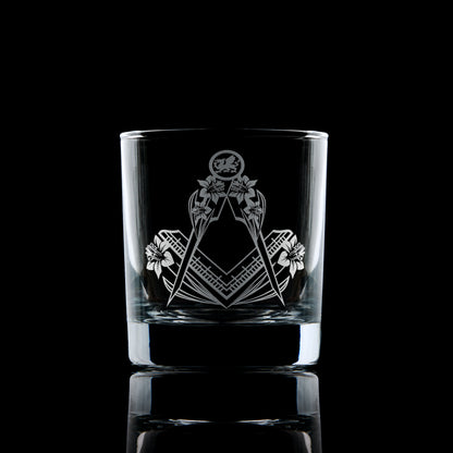 Masonic whisky glass engraved with Welsh dragon, daffodils, and Square & Compass on black background