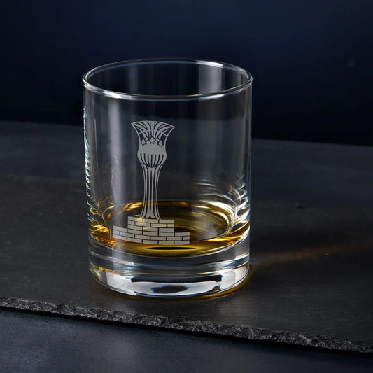 Clear glass tumbler with engraved masonic steward cup design on a dark surface