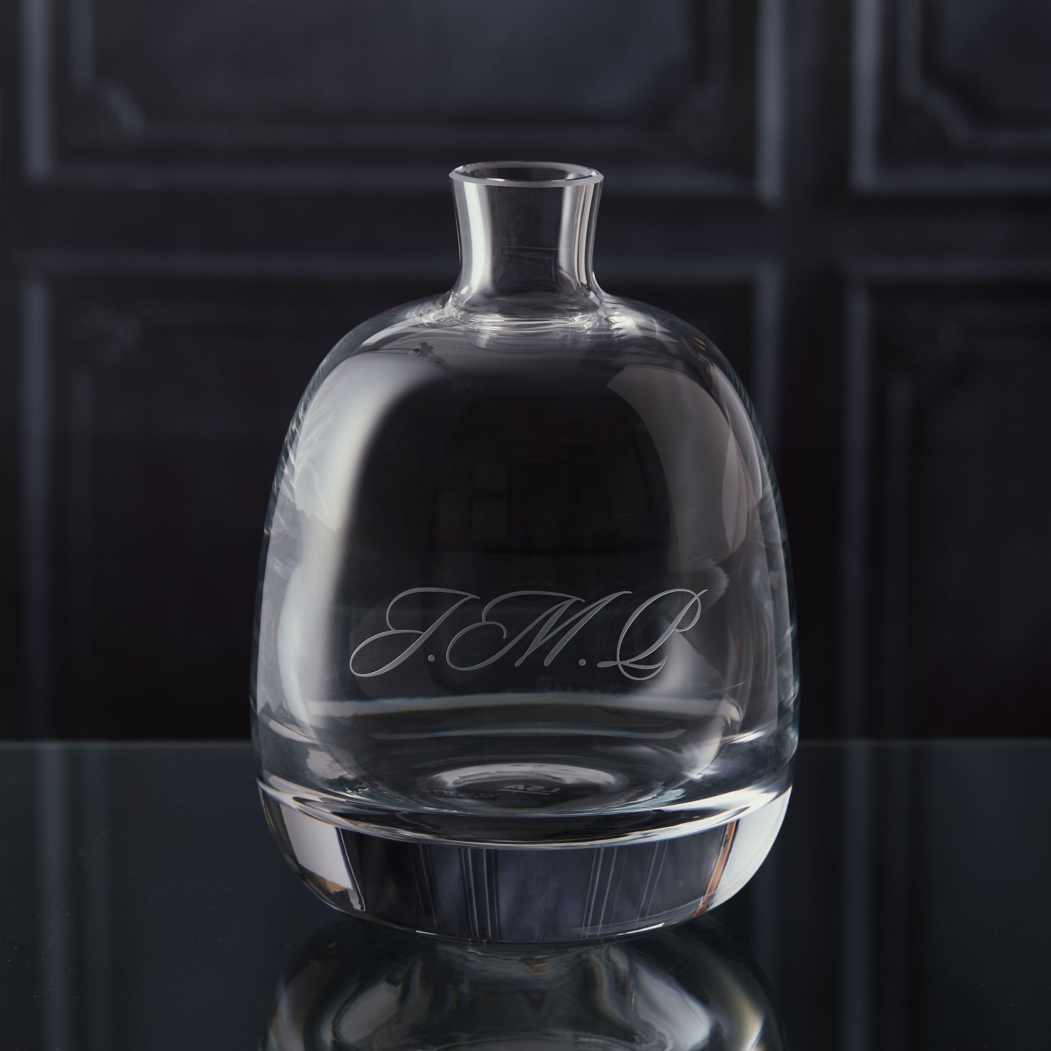 Personalised glass decanter with engraved initials text on a dark reflective surface