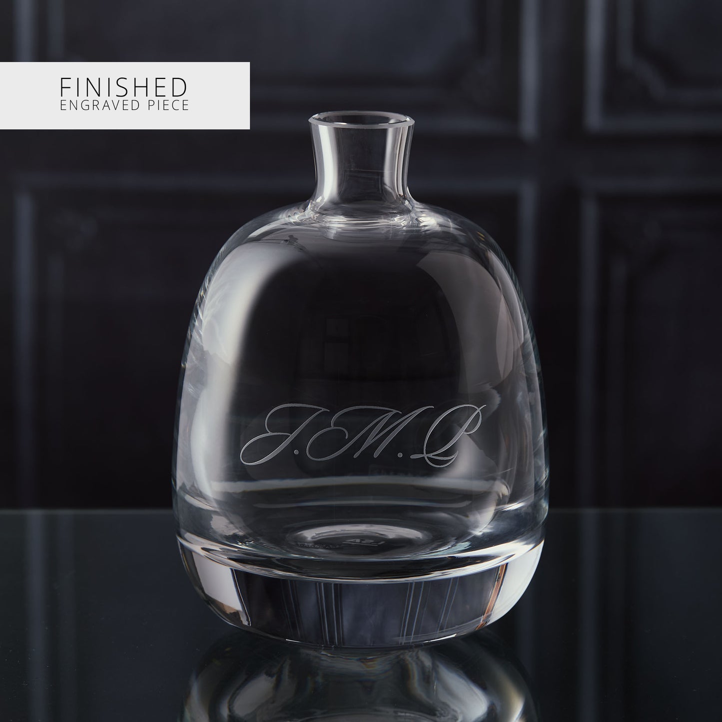 Clear glass decanter with engraved text on a dark background