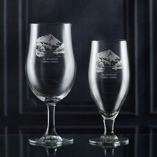 Pair of stemmed beer glasses engraved with Mt Snowdon design on a dark background