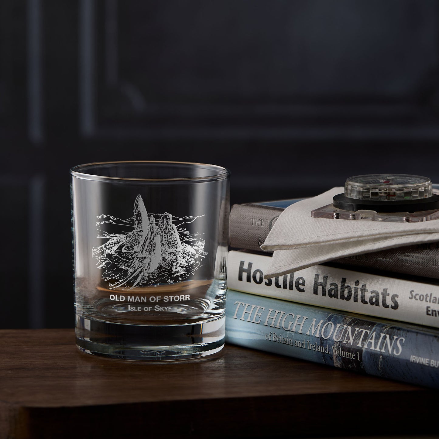 Isle of Skye whisky glass with engraved illustration of The Old Man of Storr next to a stack of mountain books