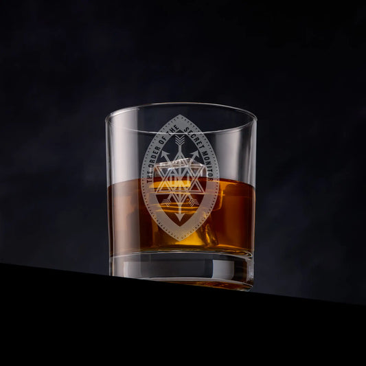Glass of whiskey with an engraved masonic order of the secret monitor grand officers collerette jewel on a dark background