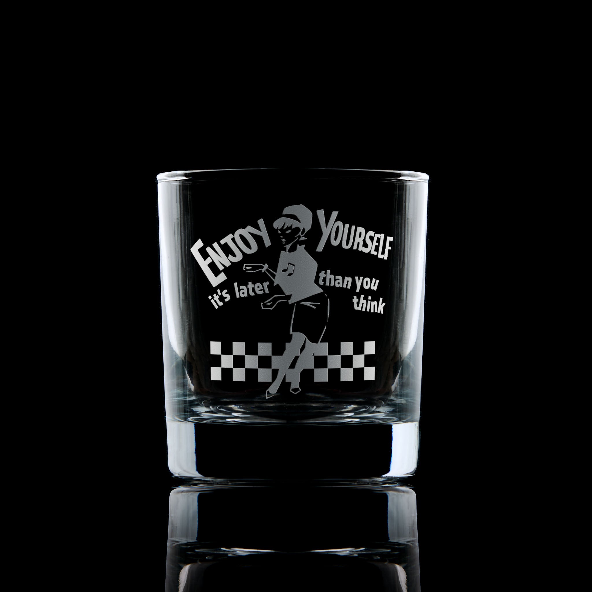 

Engraved whisky glass featuring the Original Beat Girl dancing on a checkerboard floor with the words “Enjoy Yourself"