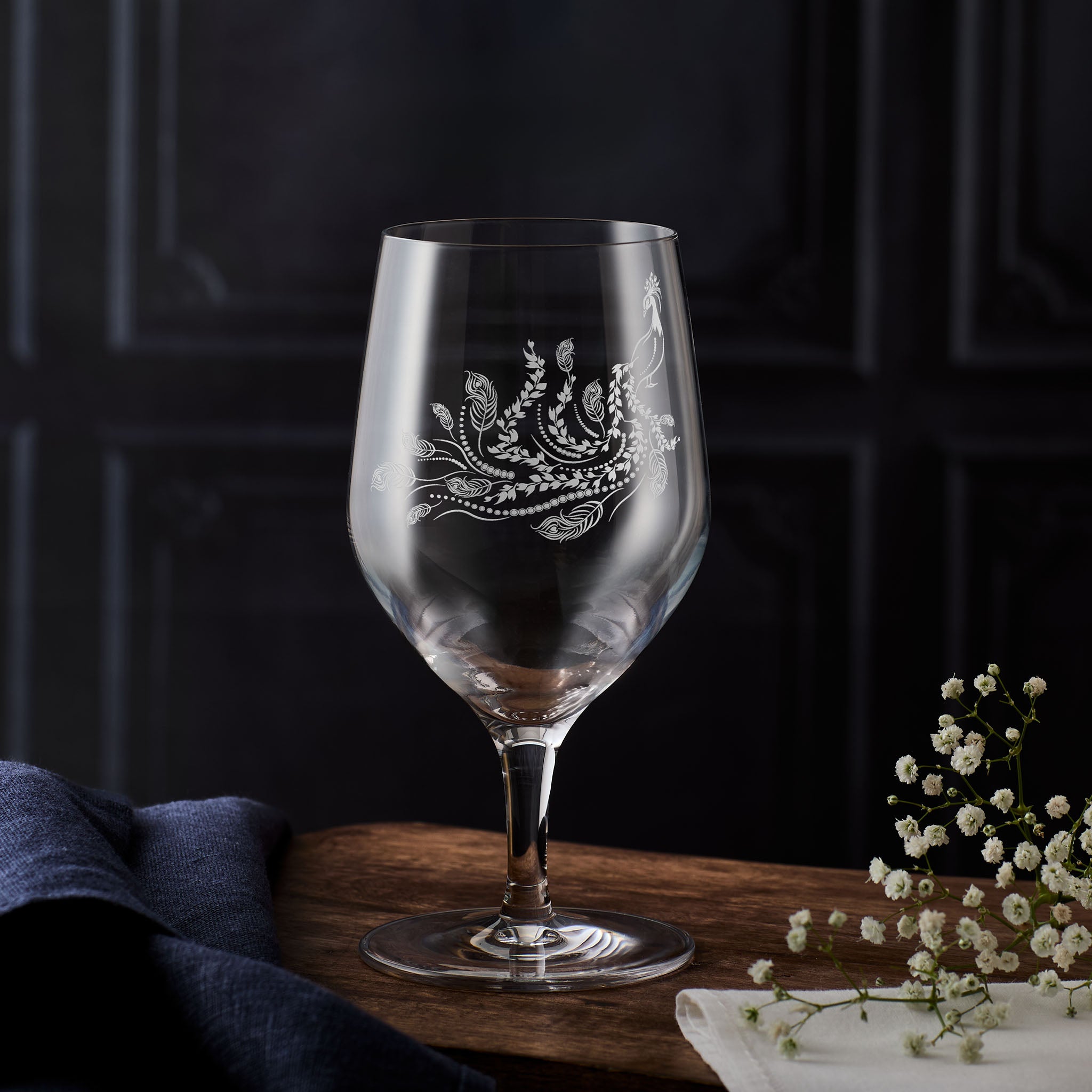 Mineral water glass engraved with a peacock and floral etching on a dark background