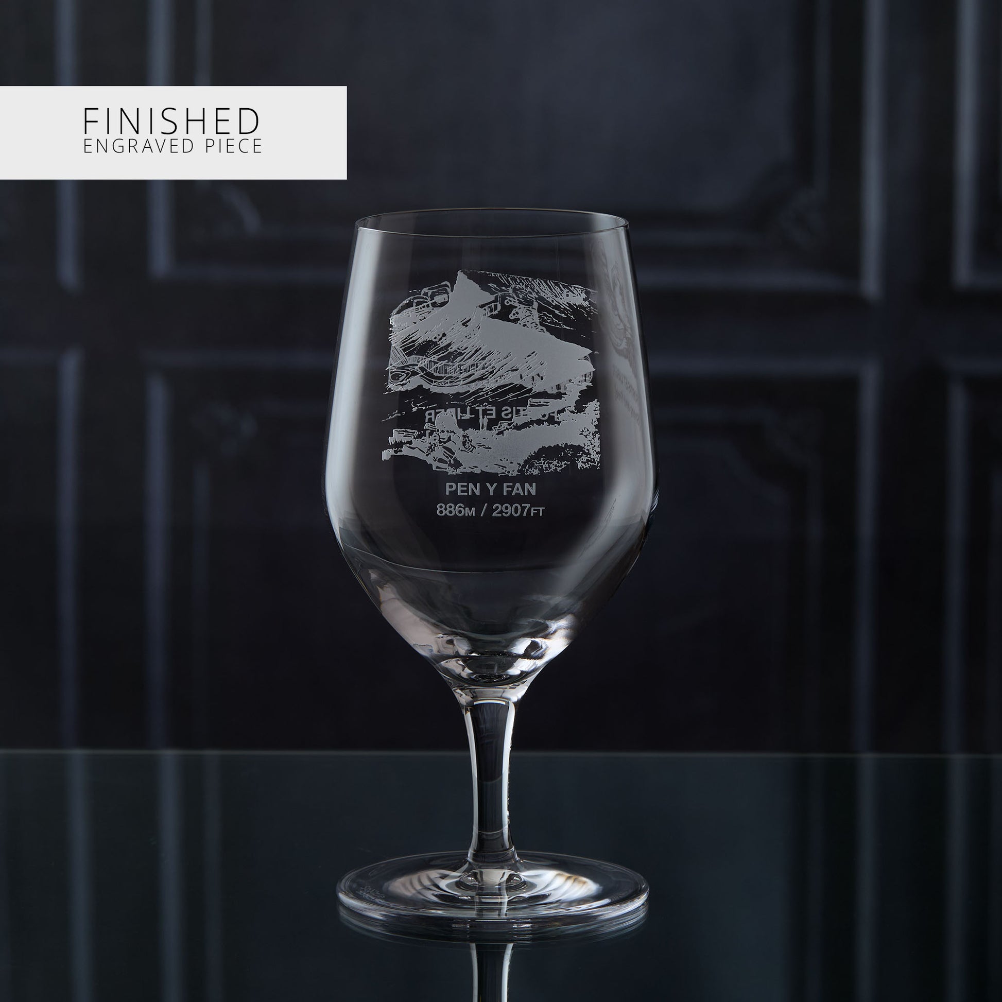 Stemmed water glass with engraved welsh mountain design on a dark background
