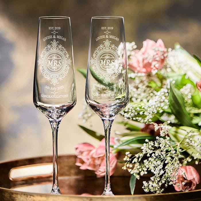 Two personalised champagne flutes with floral arrangement on a tray