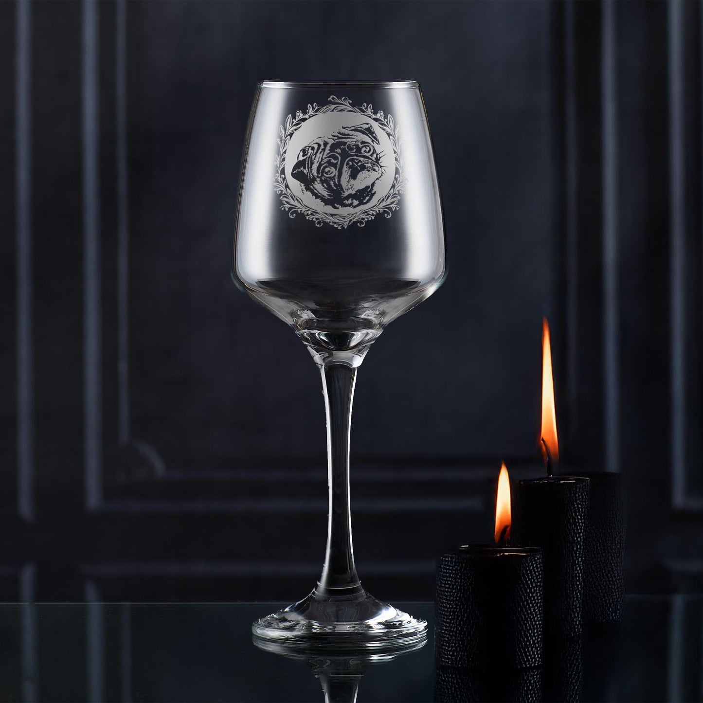Wine glass with engraved pug design on a dark background with candles