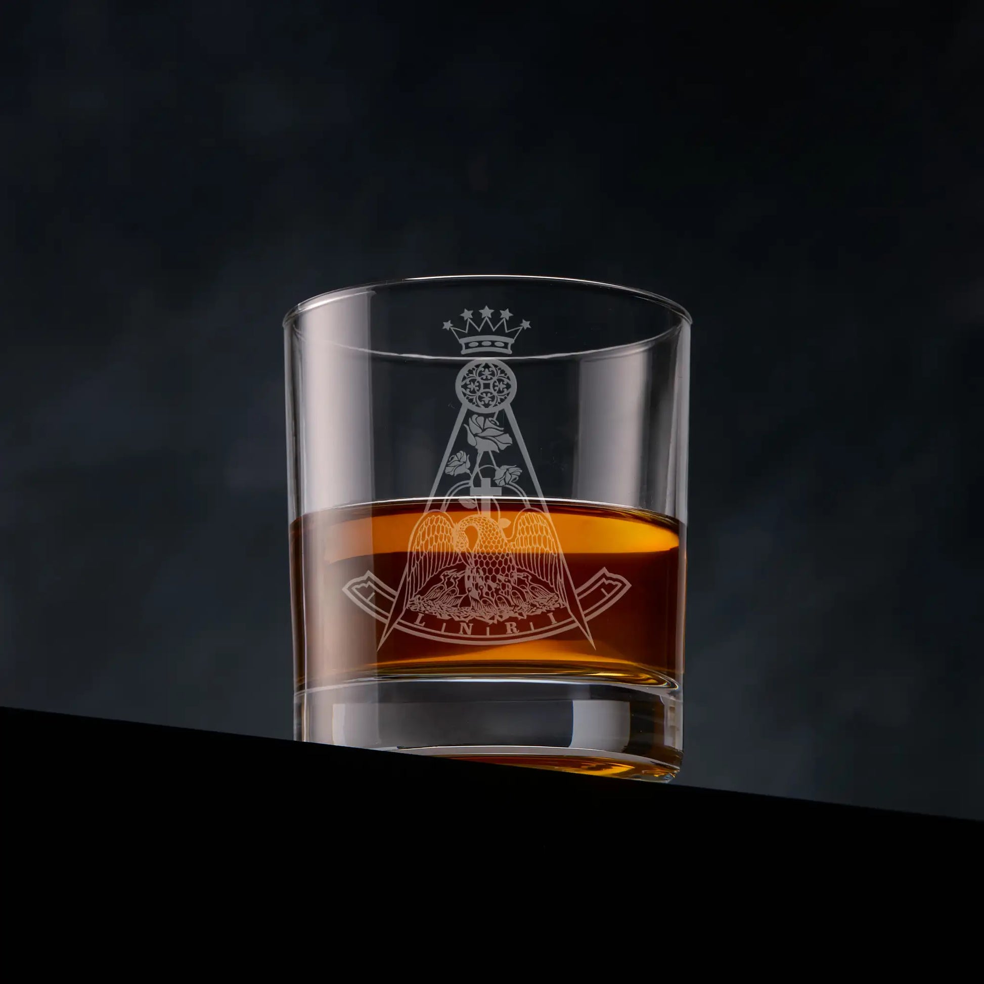 Masonic whisky glass engraved with a Rose Croix Collar Jewel, 18th degree and photographed on a dark background