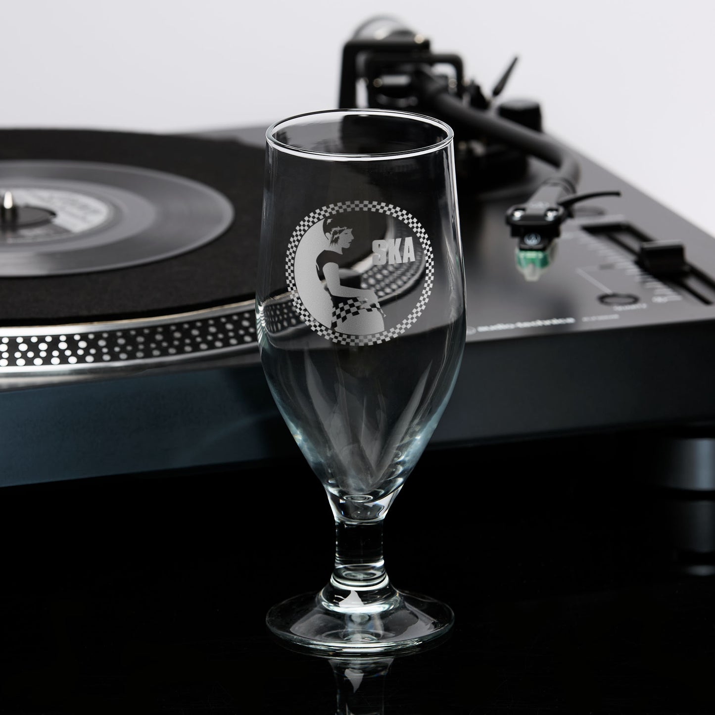 Engraved stemmed beer glass featuring a Rude Girl in checkerboard skirt, with circular checker border and Ska text