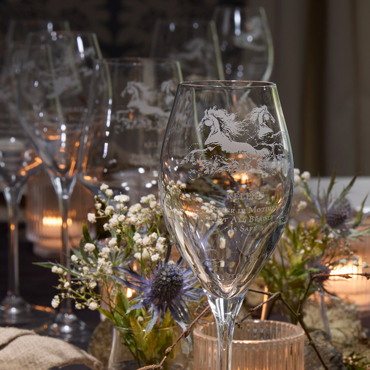 Etched prosecco glassware on a table with flowers and candles