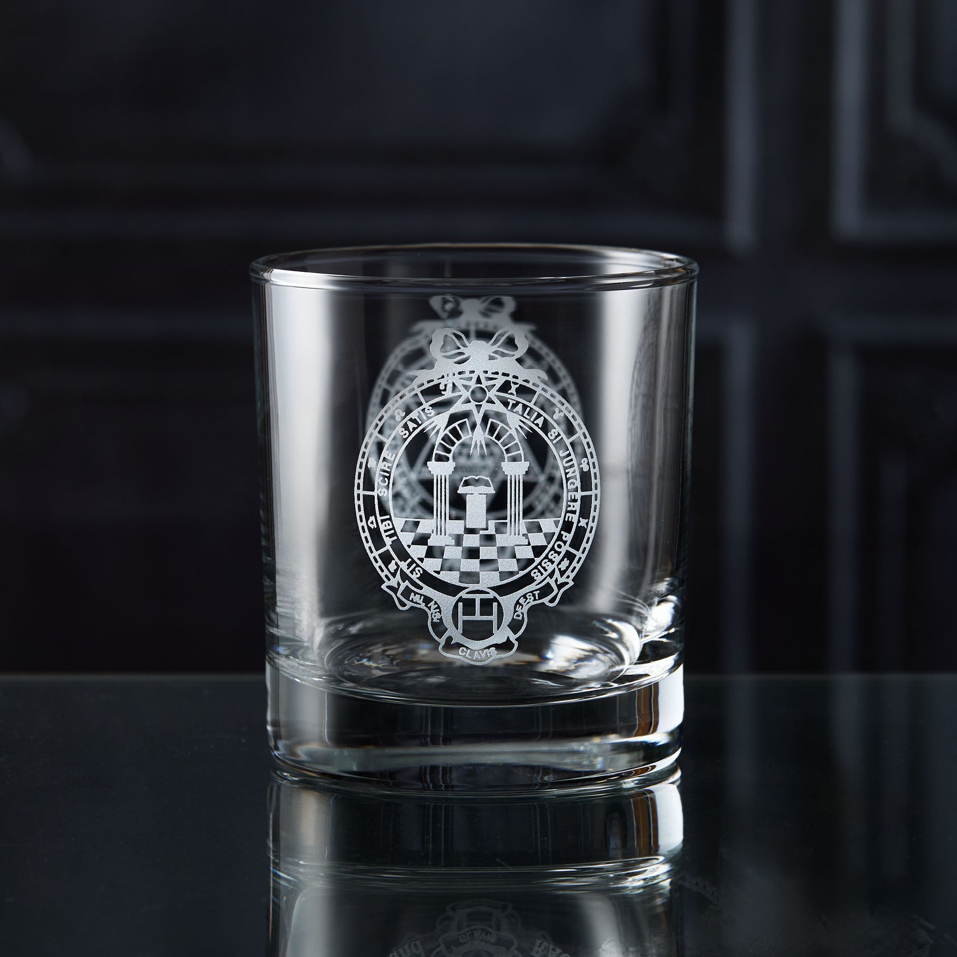 Clear glass whisky tumbler with engraved masonic royal arch design on a dark surface