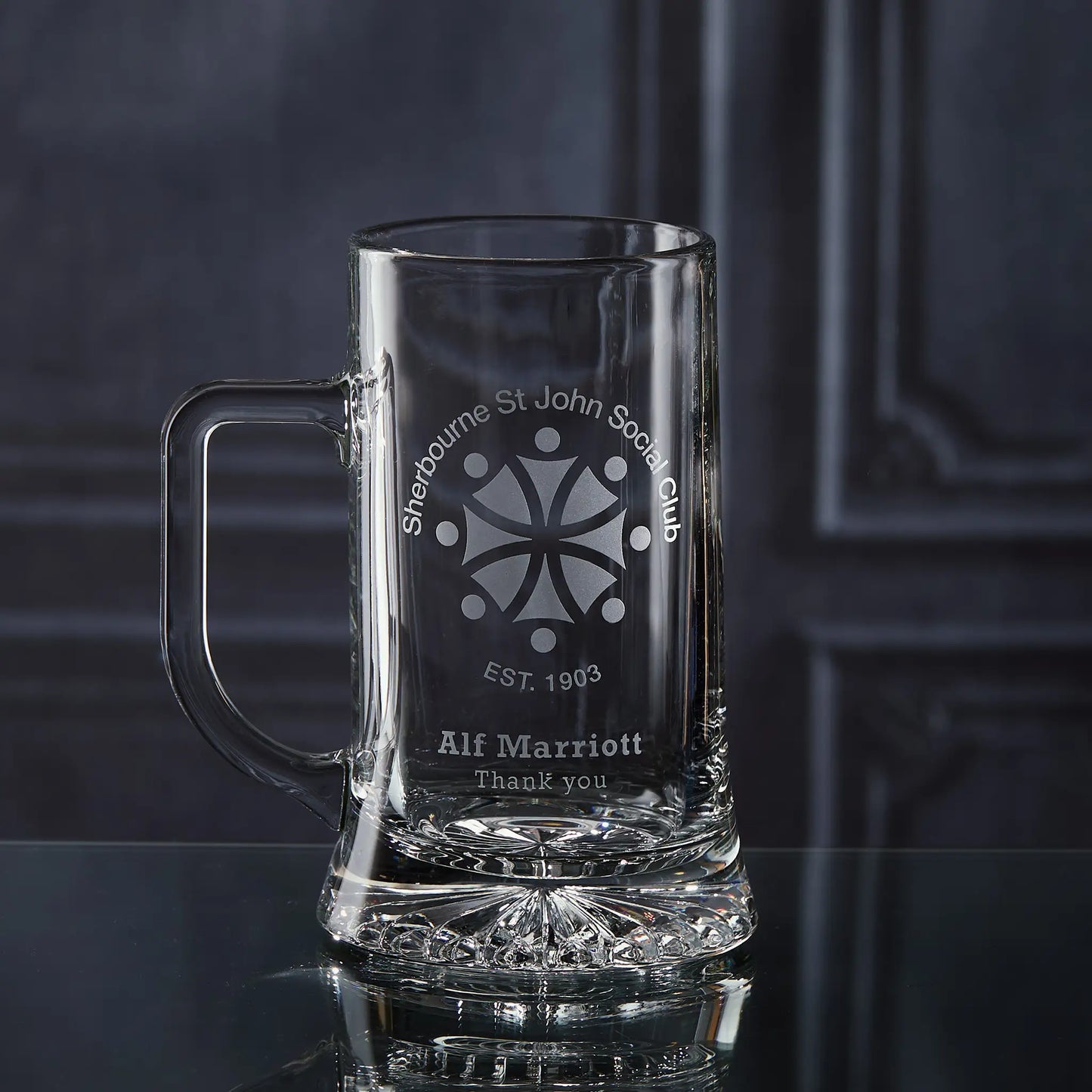 Clear glass mug with engraved corporate logo and personalised text on a dark background