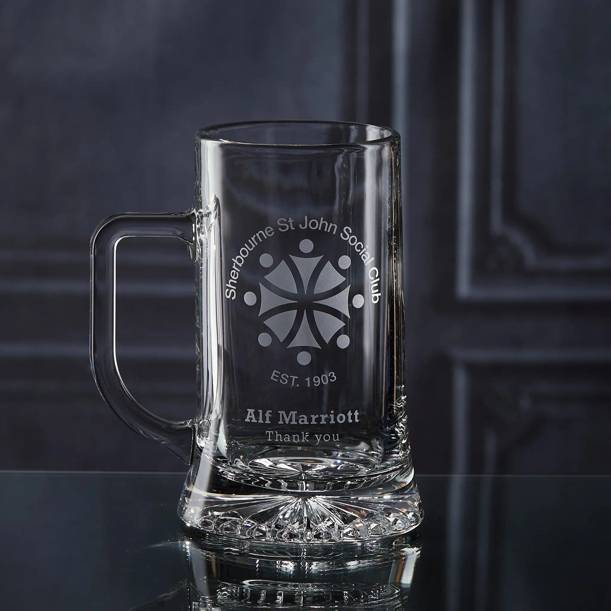 Clear glass mug with engraved corporate logo and personalised text on a dark background