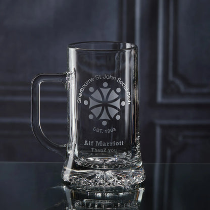 Clear glass mug with engraved corporate logo and personalised text on a dark background