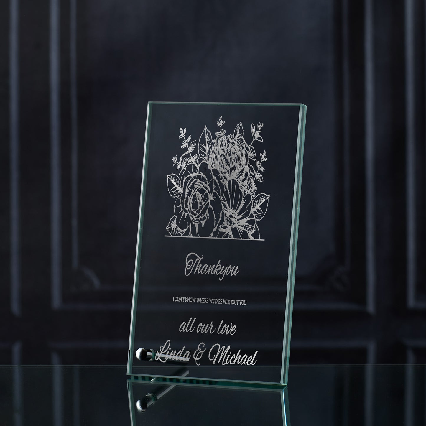 Glass plaque with floral design and engraved thankyou text on a dark background