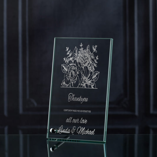 Glass plaque with floral design and engraved thankyou text on a dark background