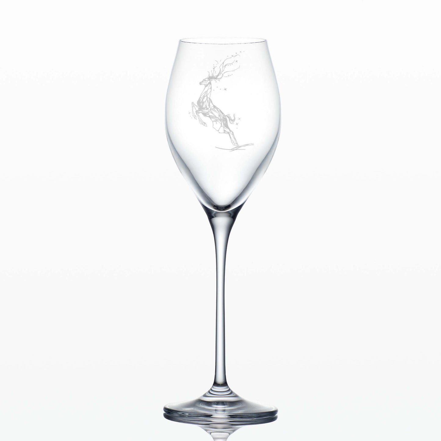 Tall engraved prosecco glass featuring a Winter Stag leaping ithrough stars on a white background