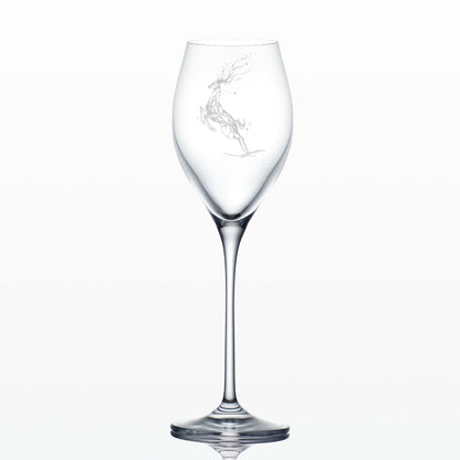 Tall engraved prosecco glass featuring a Winter Stag leaping ithrough stars on a white background