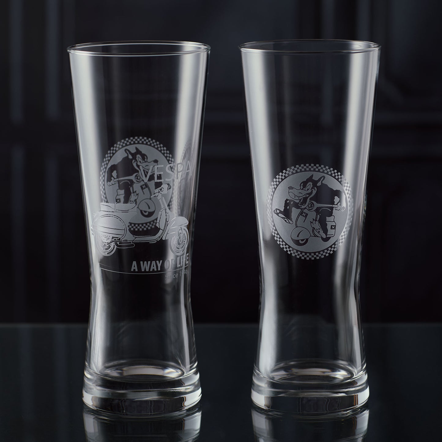 Two clear pint glasses with a Vespa and scooter club logo on a black background