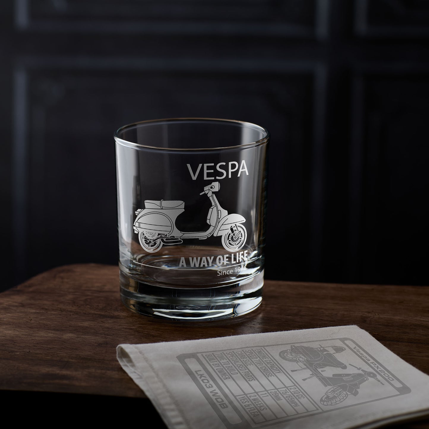Vespa t5 glass with scooter design and personalised text on a wooden surface with a dark background