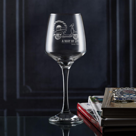 Engraved wine glass featuring Vespa Rally 200, styled next to scooter books in a lifestyle setup