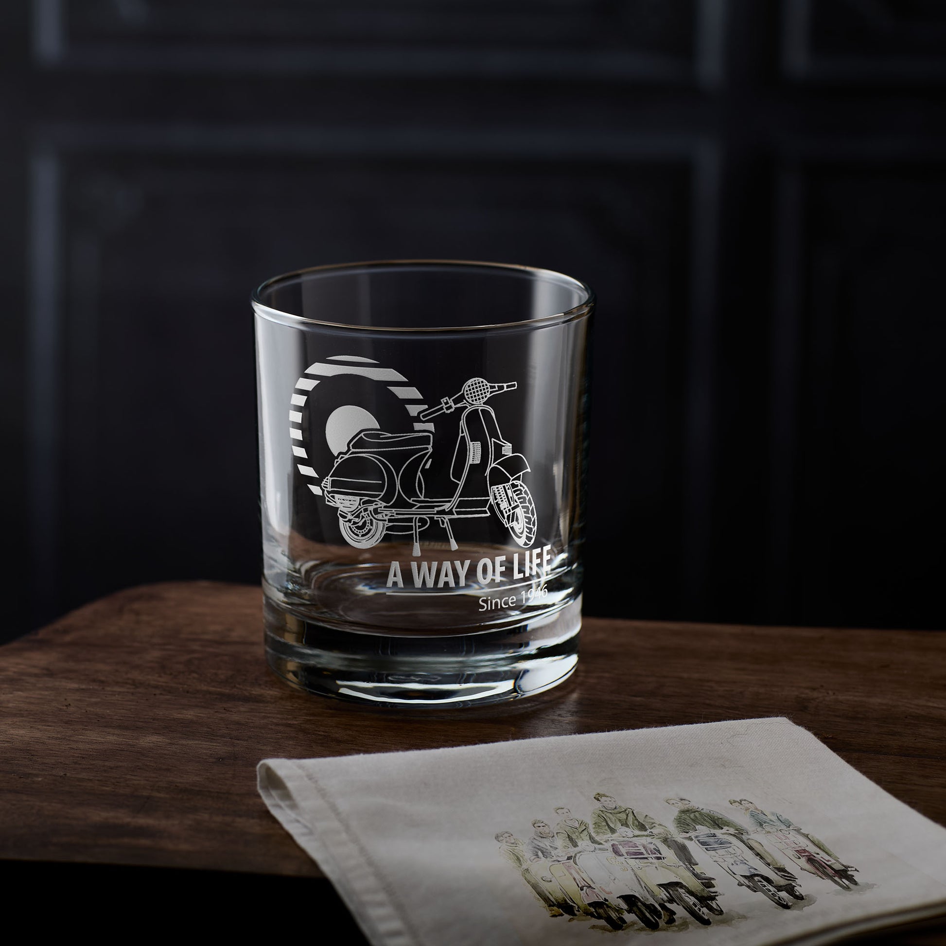 Vespa t5 whisky glass with scooter design and 'A way of Life' text on a wooden surface with a dark background