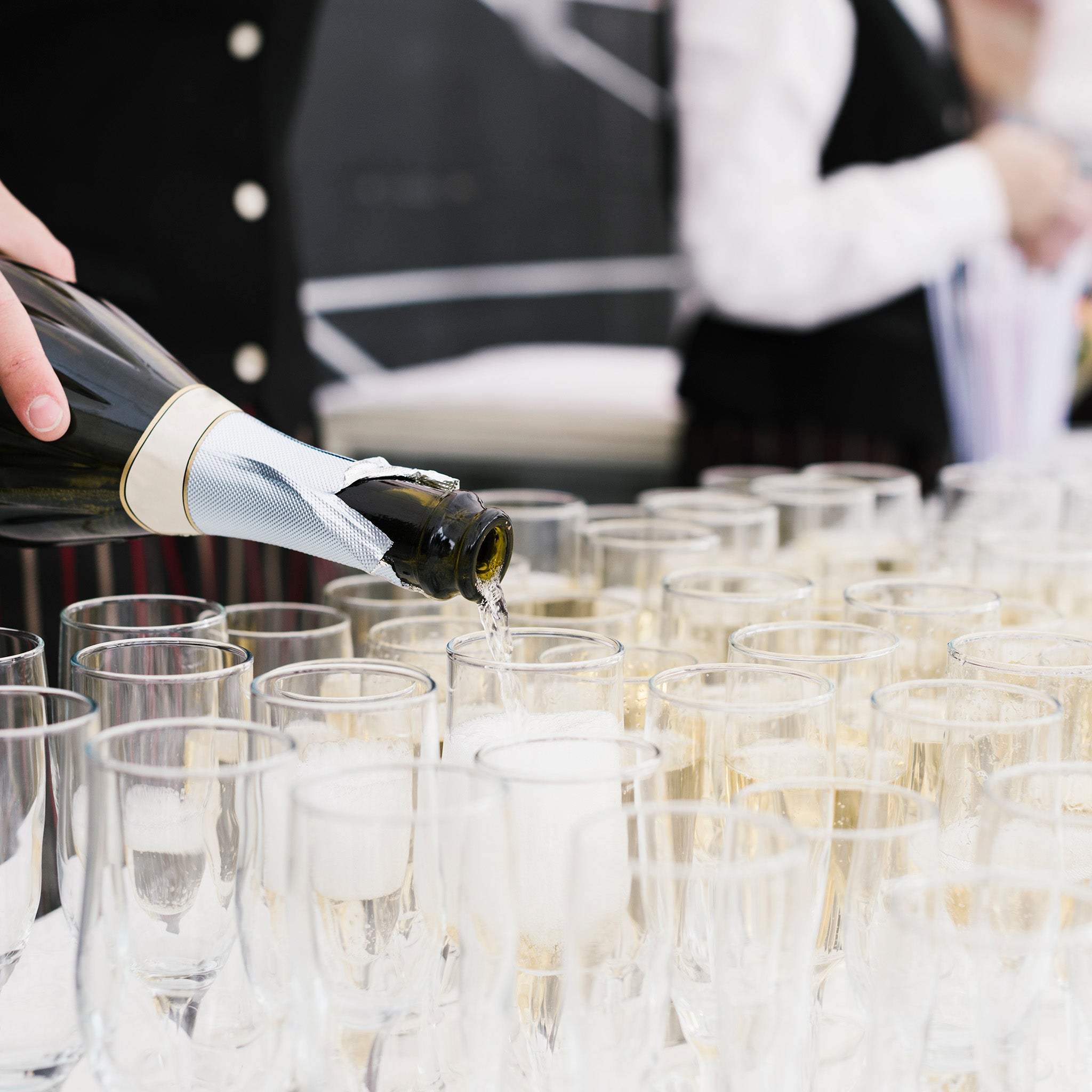 Person pouring champagne into glasses at a formal event