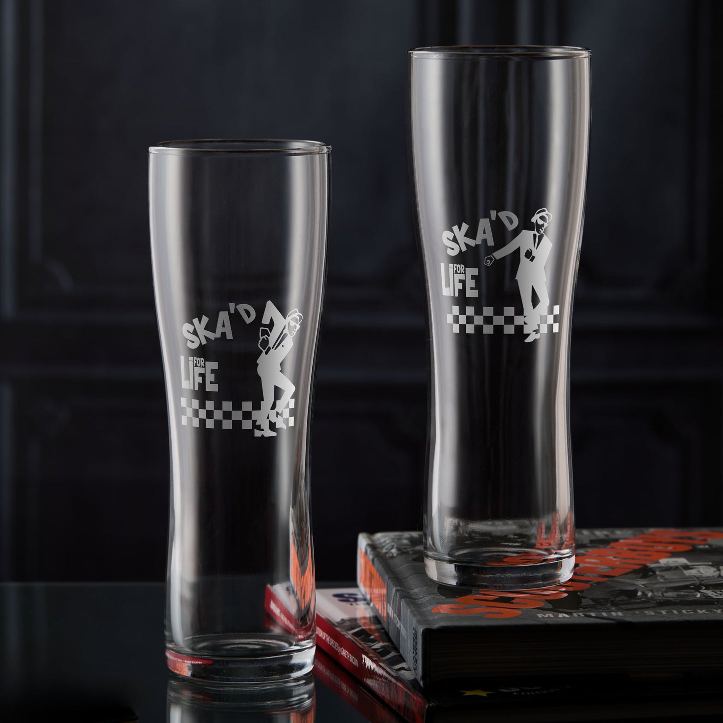 Two Walt Jabsco pint glasses with 'Ska'd for Life' text and checkered design on a dark background