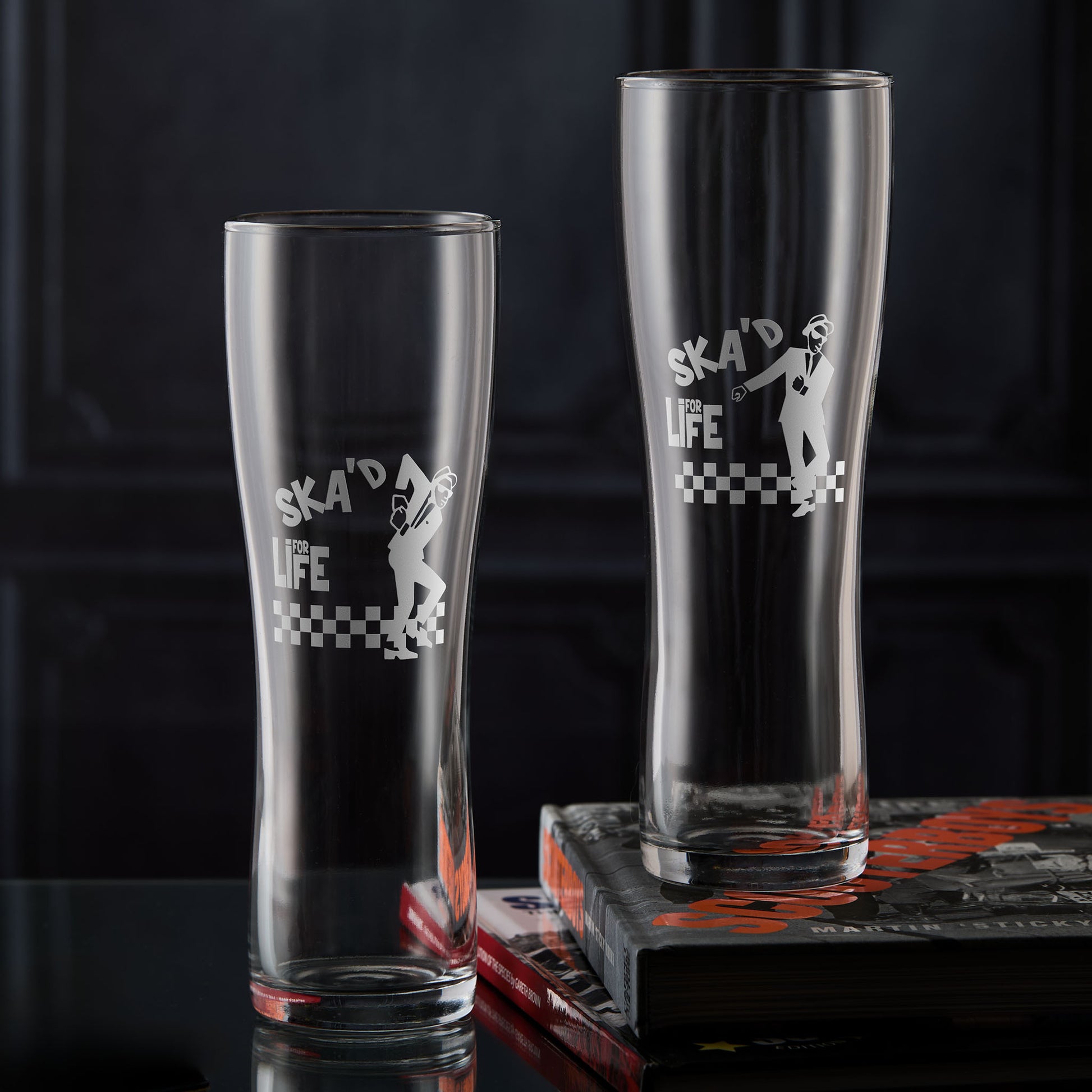 Two Walt Jabsco pint glasses with 'Ska'd for Life' text and checkered design on a dark background