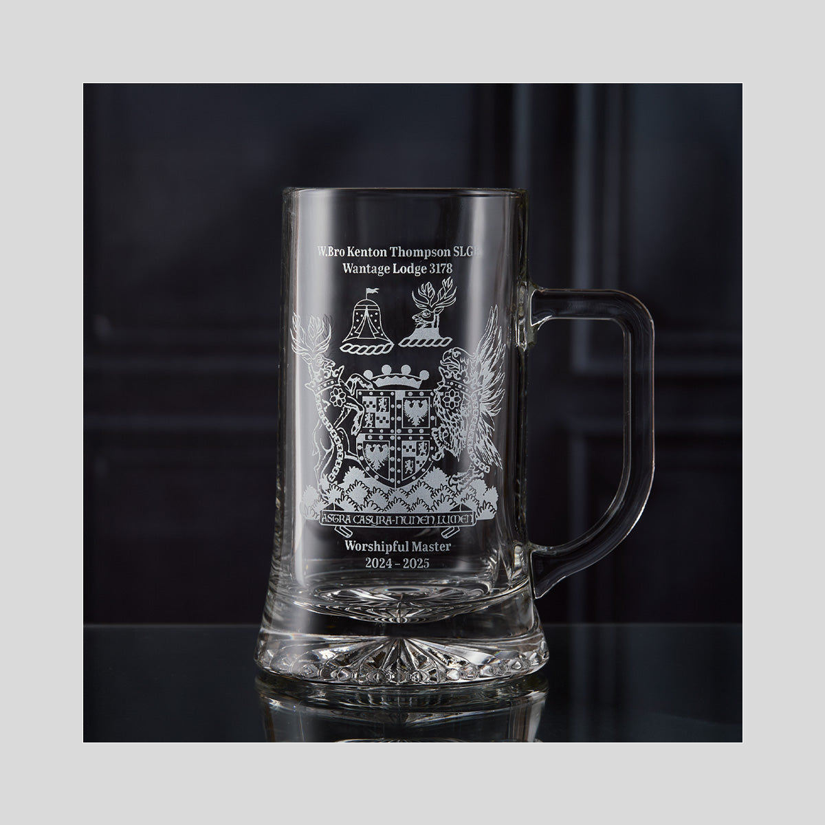 Clear glass Masonic tankard with engraved crest design on a dark background