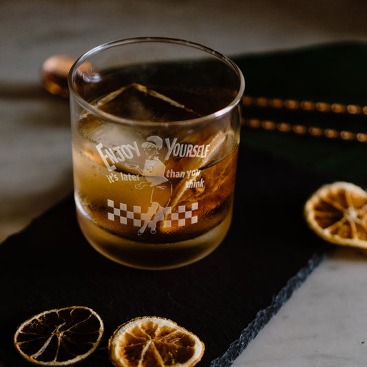 Engraved whisky glass featuring the Original Beat Girl dancing on a checkerboard floor with the words “Enjoy Yourself"