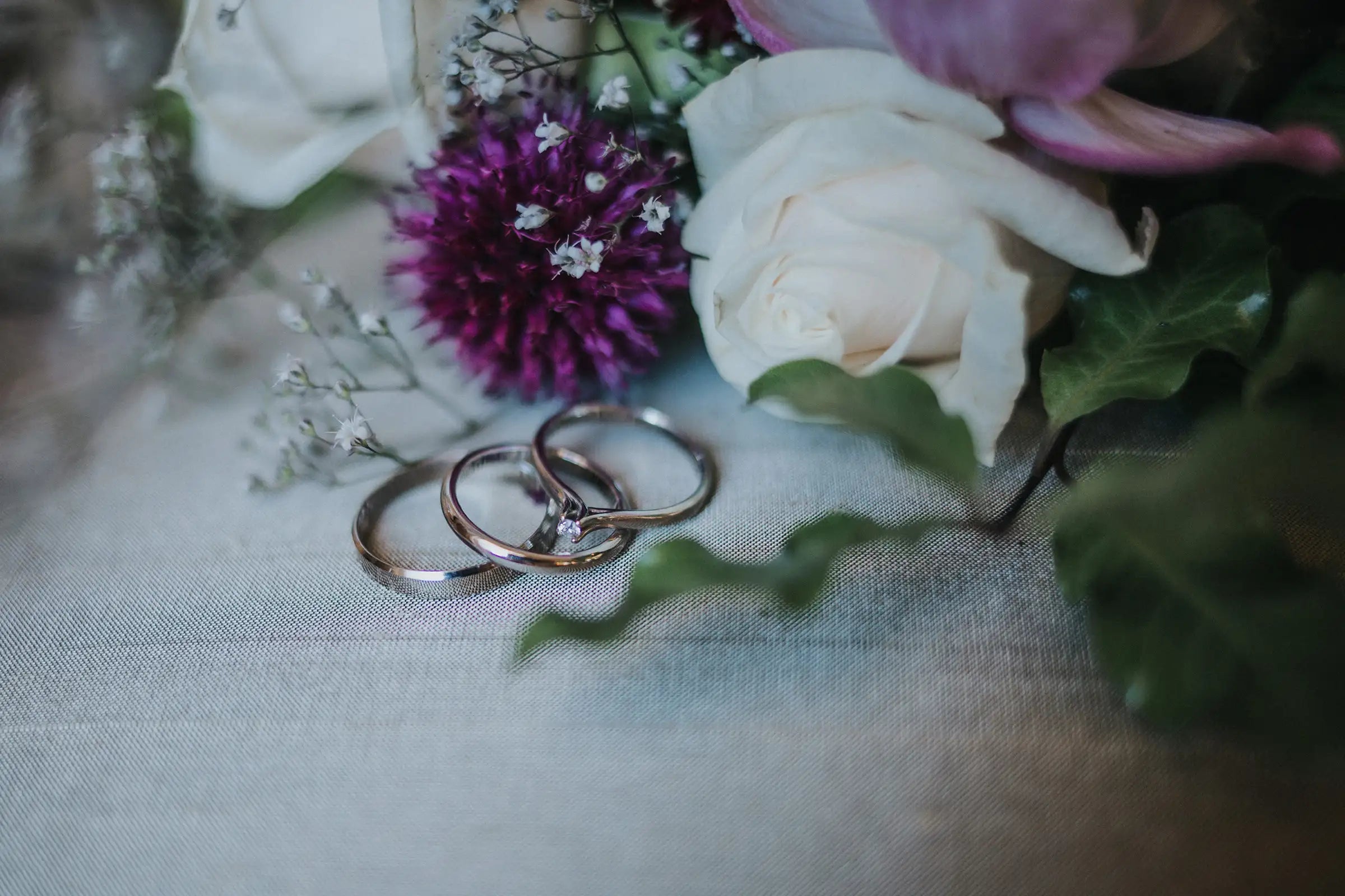 Flowers with wedding rings on a textured surface