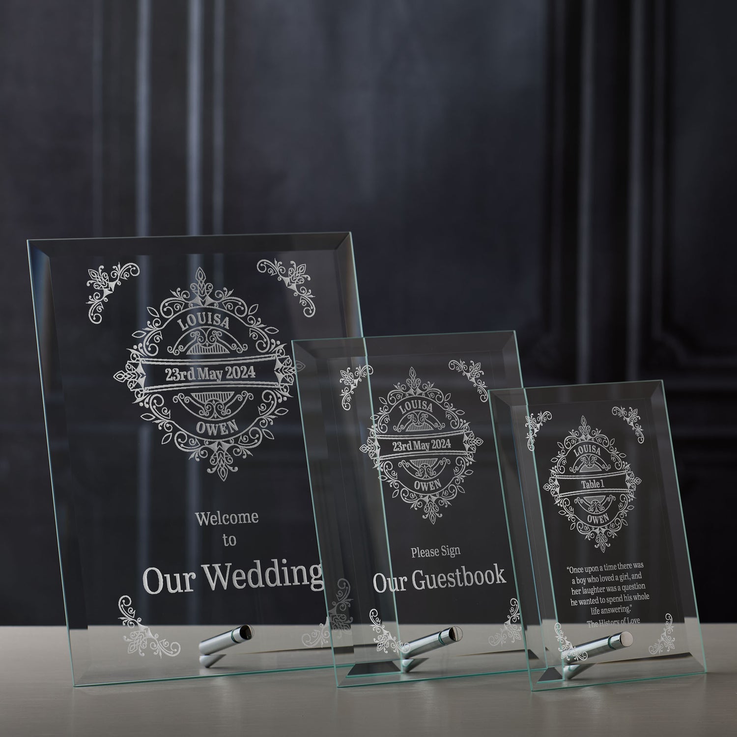 Three glass wedding signs with engraved text on a dark background