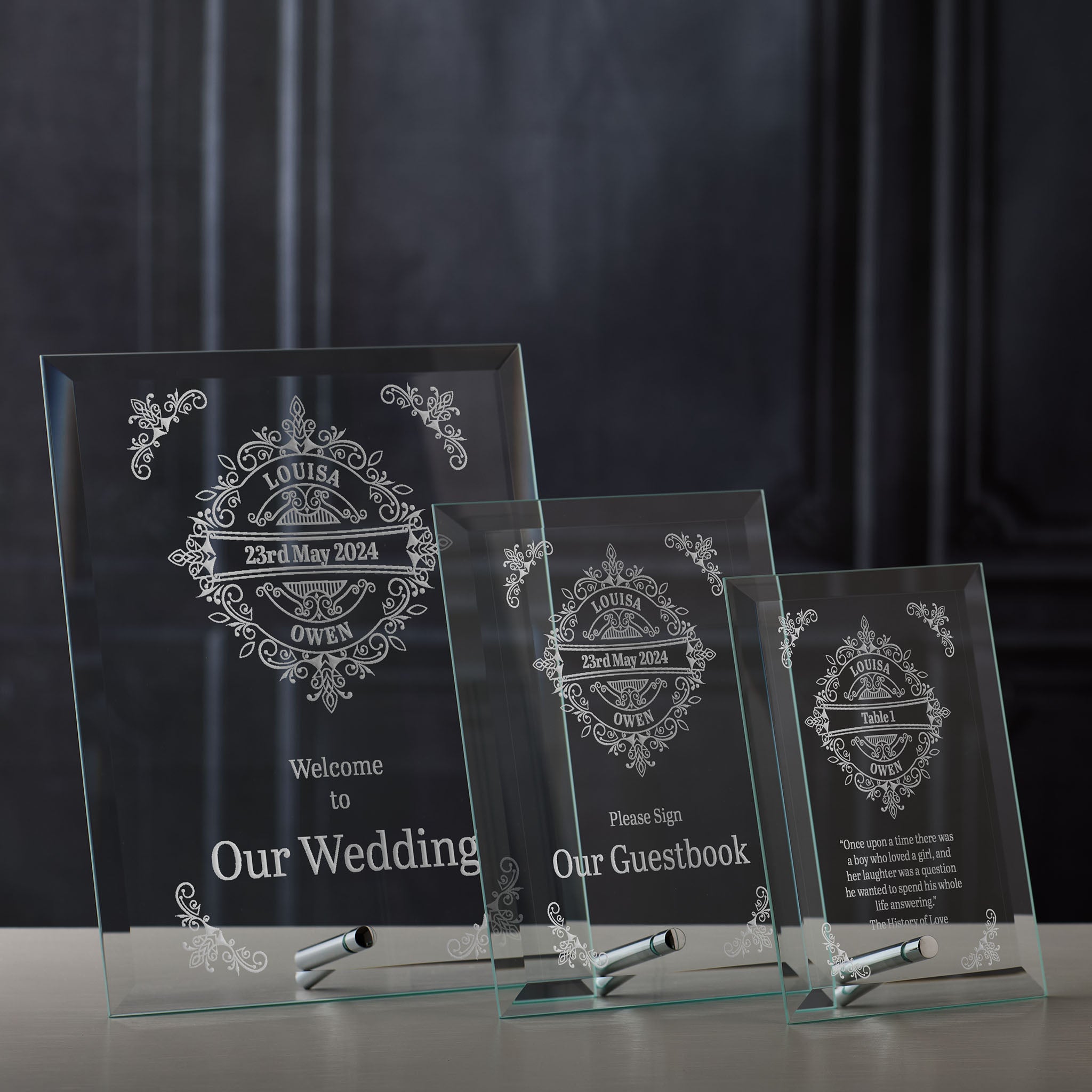 Three glass wedding signs with engraved text on a dark background
