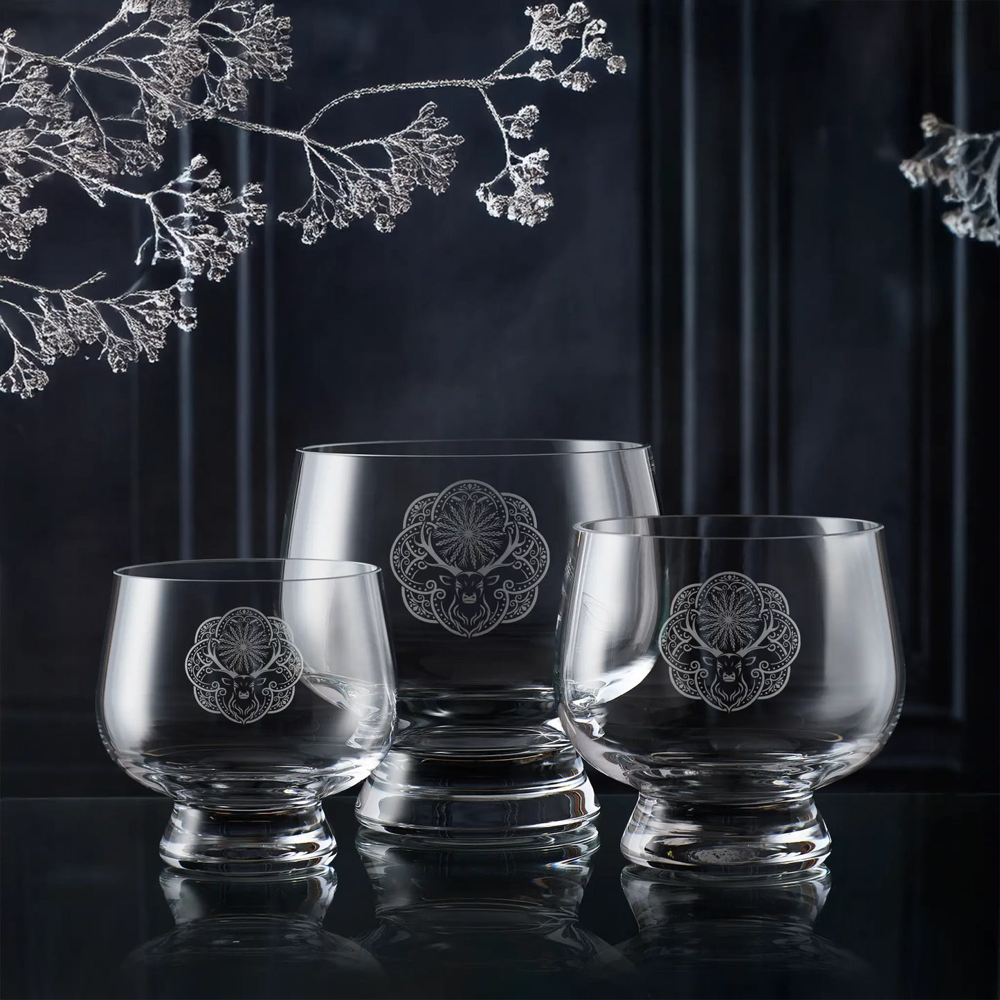 Set of three glass bowls engraved with Christmas deer design with floral etching on a dark background