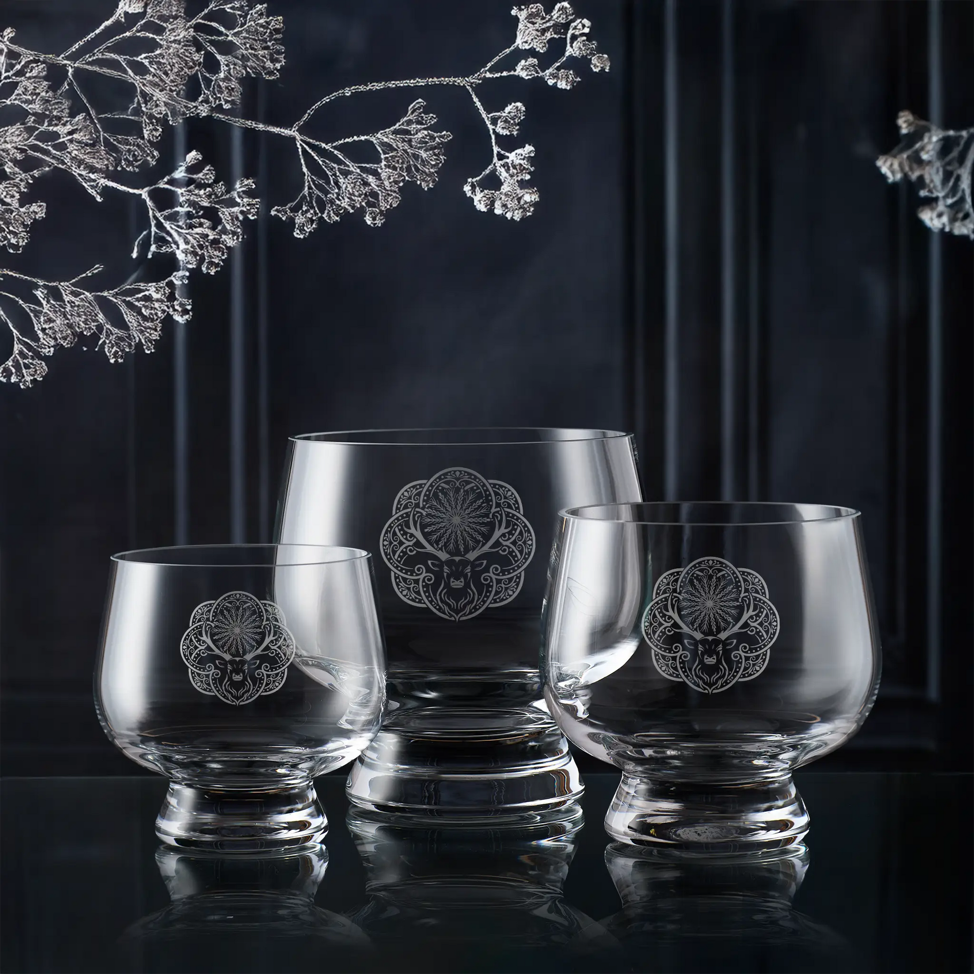 Set of three glass bowls engraved with Christmas deer design with floral etching on a dark background